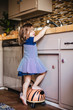© Maskot - Girl standing by kitchen counter