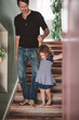 © Maskot - Father holding hands with daughter while climbing steps at home
