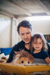© Maskot - Father reading book with daughter while sitting in bedroom