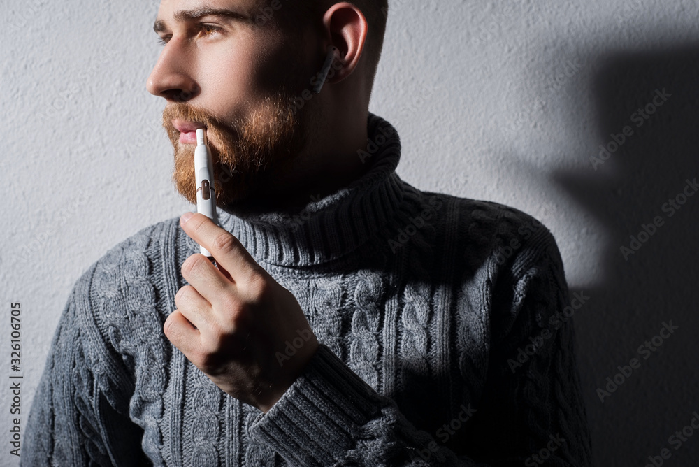 close-up. Art portrait of a young bearded guy smoking a modern high-tech  electronic cigarette iqos Stock Photo