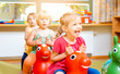 © Kzenon - Little girls riding on play horses in kindergarten