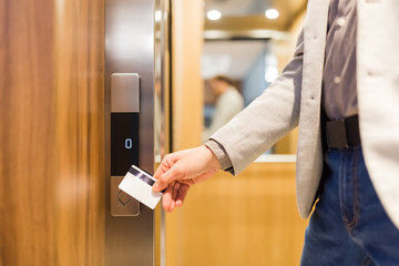 Close up of businessman hand holding key card to unlock elevator access, corporate building security concept.