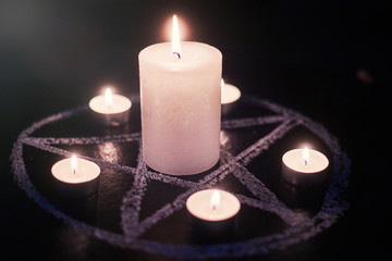 Pentagram and burning candles. The magical ritual of Satanism, invocation of spirits, spiritualistic sessions.