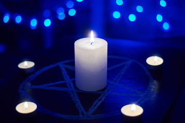 Pentagram and burning candles. The magical ritual of Satanism, invocation of spirits, spiritualistic sessions.