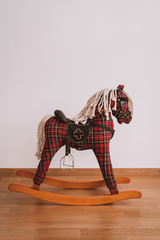 Rocking horse with tartan fabric on wooden floor with white background, children toy