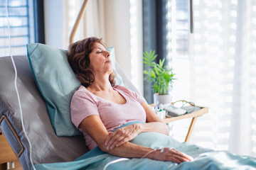 Wall Mural - A female patient with IV drip lying in bed in hospital room.