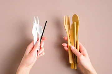 Disposable plastic cutlery set vs reusable bamboo tableware comparison concept. Flat lay, top view.