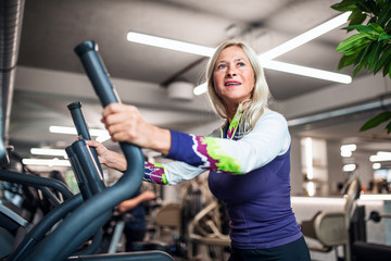 Poster - A senior woman in gym doing cardio work out exercise.