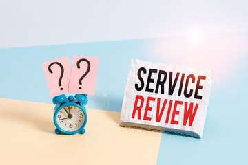 Writing note showing Service Review. Business concept for an option for customers to rate a company s is service Alarm clock beside a Paper sheet placed on pastel backdrop