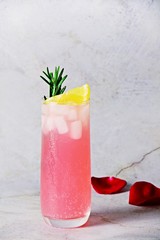 Wall Mural - Refreshing glass of rose lemonade with ice cubes, lemon and rosemary