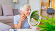 © Dragana Gordic - Senior female looking at sagging skin face in mirror, old age appearance. Portrait of senior woman applying anti-aging cream. Portrait of an attractive middle aged woman looking into a mirror