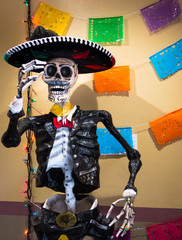 Traditional mexican skeleton sculpture with Mariachi outfit and Sombrero in market alley celebrating Dios de los Muertos