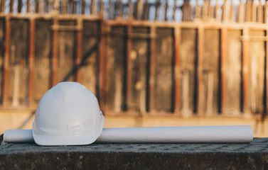 White helmet on the blueprint in construction site background , safety first concept