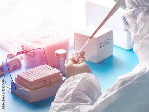 Fotografía Epidemiologist in protective suit, mask and glasses works with patient swabs to detect specific region of 2019-nCoV virus causing Covid-19 viral pneumonia