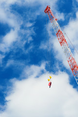 Construction crane with hook at work among clouds (with copy space)