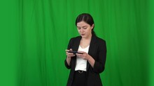 Beautiful Girl In A Business Suit Works On A Smartphone. Background - Green Screen For Keying.