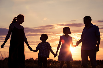 Wall Mural - Happy family standing on the field at the sunset time. They build a house.