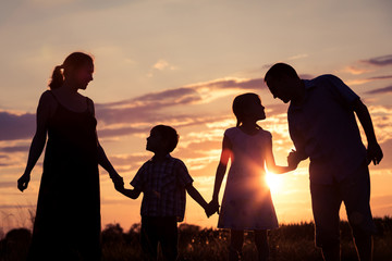 Wall Mural - Happy family standing in the park at the sunset time.