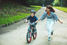 Mother Teaching Son How To Ride Bicycle