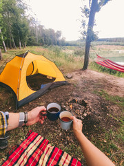 Wall Mural - friends hands holding metal mugs with tea campfire with ten on background