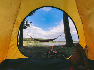Wall Mural - view form camping tent on campfire with hammock near lake
