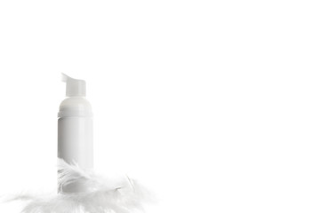 Wall Mural - White cosmetics bottle with dispenser. Unbranded flacon with feathers on light mockup. Blank pack for nourishing or moisturizing lotion, soft cosmetic foam, balm. Skincare product concept. Copy space