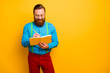 © deagreez - Photo of attractive guy holding writing notes in personal planner have creative idea for new project wear bright blue shirt green suspenders red pants isolated yellow color background