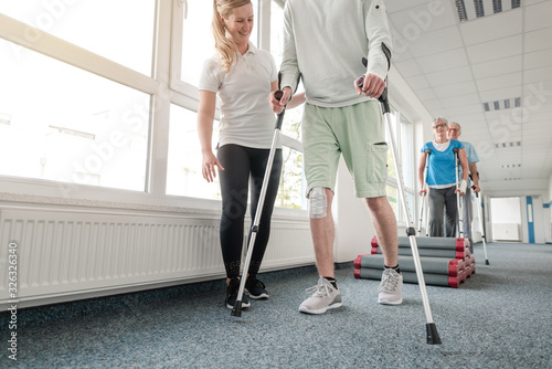 Fotomural People in rehabilitation learning how to walk with crutches