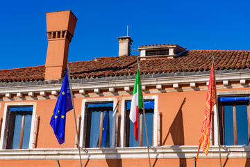 A building with flags of European Union, Italy, and Venice