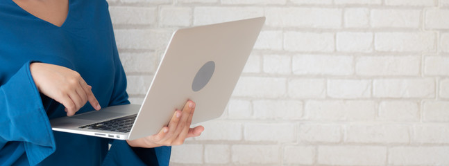 Wall Mural - Beautiful asian young woman using laptop standing at workplace on cement concrete background, girl happy with computer internet online, lifestyle and freelance business concept, banner website.