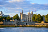 Fototapeta Londyn - Colourful view of the Tower of London, a castle and a former prison in London, England, from the River Thames at sunset. The Tower of London, today a museum, houses a collection of crown jewels