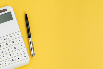 flat lay or top view of black pen with white calculator on vivid yellow background table with blank 
