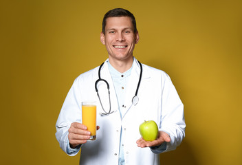 Poster - Nutritionist holding glass of juice and apple on yellow background