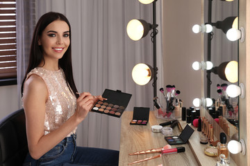 Poster - Beautiful young woman applying makeup near mirror in dressing room