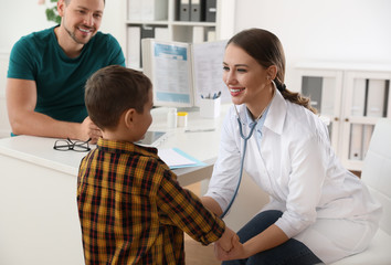 Canvas Print - Father and son visiting pediatrician. Doctor examining little patient with stethoscope in hospital