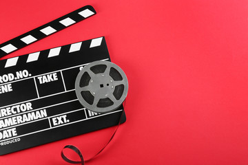 Wall Mural - movie clapper and reel on red background, top view. space for text