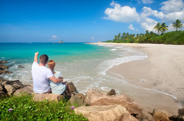 Wall Mural - Couple tourists resting during summer vacation on beach of island Sri Lanka.