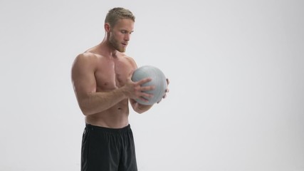 Wall Mural - A focused serious young fit sportsman doing exercises with grey fitness ball isolated over white background