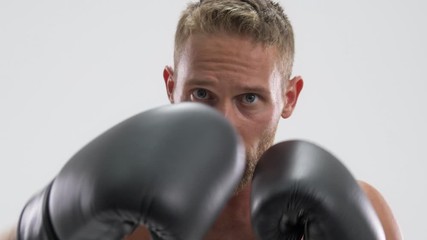 Wall Mural - A focused young fit sportsman is doing boxing exercises isolated over white background