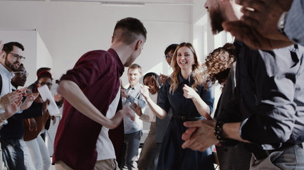 Happy fun young businessman dancing with multiethnic team of business people at office party slow motion RED EPIC.