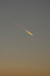 Wolkenloser Himmel nach Sonnenuntergang bei Abendrot und Blaue Stunde mit Flugzeug mit Kondensstreifen die angestrahlt von den letzten Sonnenstrahlen glühen wie ein Komet oder Feuerball mit Schweif