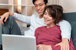 © Drobot Dean - Photo of joyful multinational couple laughing and using laptop