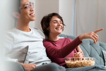 Poster - Photo of joyful multinational couple eating popcorn and watching movie