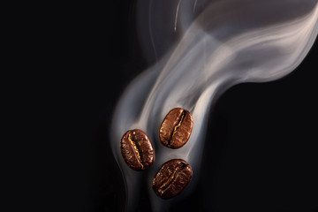 Roasted coffee beans. Seeds of freshly roasted coffee with smoke. Coffee beans closeup with emphasis on the grain with smoke.