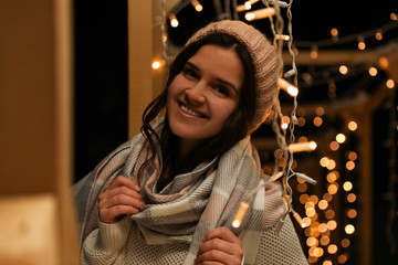 Sticker - Young woman wearing warm sweater, hat and scarf  outdoors at night. Winter season