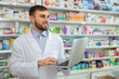 © New Africa - Professional pharmacist with laptop in modern drugstore