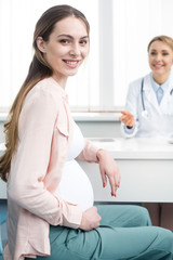 Wall Mural - happy pregnant woman having consultation with gynecologist in clinic