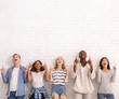 © Prostock-studio - Group of multiracial friends pointing up at copy space