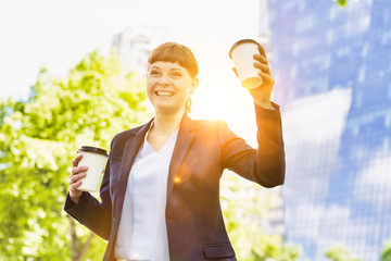 Young beautiful businesswoman holding two cups of coffee