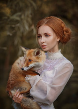 Close Up Portrait Of Amazing Cute Young Woman In Beautiful Fairy-tale Image With Fire Red Hair In White Lace Dress Looks Far Away And Holds Small Red And White Fox In Beautiful Yellow Autumn Forest